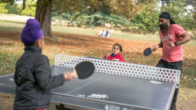 Family playing table tennis at Osterley Park and House, London in summer